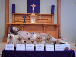 Relics are from left to right:  From the Table of the Last Supper, From the Basin of the Foot Washing, From the Column of the Flagellation, a portion of the Holy Sponge, From the Shaft of the Holy Lance, From the Title of the Cross of Our Lord (Titulus Crucis), From the Holy Sepulchre, From the Cross of the Good Thief.  The two very large veiled reliquaries on the altar which can only barely be seen, are a piece of the True Cross, and a complete Thorn from the Holy Crown of Thorns.